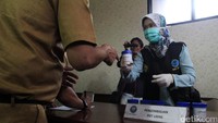 Seorang PNS mengambil wadah untuk urine.