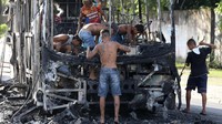 Sejumlah warga Brasil nampak mengumpulkan sisa-sisa besi dari bus yang terbakar di kawasan Fortazela, Kamis (20/4/2017). REUTERS/Paulo Whitaker.