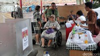 Seorang warga datang dengan menggunakan kursi roda. Dia tampak dibantu oleh kerabatnya menuju bilik suara.