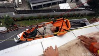 Salah seorang korban diturunkan dengan tandu dan tali seling dari lantai atas.
