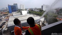Petugas menyemprotkan air dari salah satu sisi gedung yang terbakar dalam simulasi penghentian bencana kebakaran.