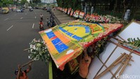 Beberapa petugas menurunkan karangan bunga dari atas truk untuk diletakkan di depan pagar Monas.