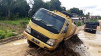 Truk pengangkut minyak terjebak di tengah jalan, karena tersangkut timbunan tanah becek.