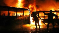 Kekerasan terjadi di Brasil di akhir aksi pemogokan umum yang pertama kali dilakukan di negara tersebut sejak 20 tahun terakhir. Nampak petugas pemadam terlihat berjibaku memadamkan api pada bus-bus yang dibakar. Mario Tama/Getty Images.