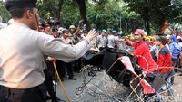 Seorang polisi berusaha menenangkan massa buruh.