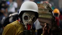 Demonstran berdemo dengan memakai topeng. REUTERS/Carlos Garcia Rawlins.