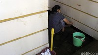 Seorang warga nampak membersihkan sisa lumpur di teras rumahnya. Pool/Wisma Putra.