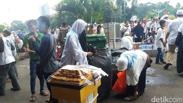 Beberapa massa memunguti sampah yang berada di halaman Masjid Istiqlal. 