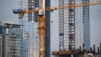 Alat berat bekerja menyelesaikan pembangunan gedung bertingkat.