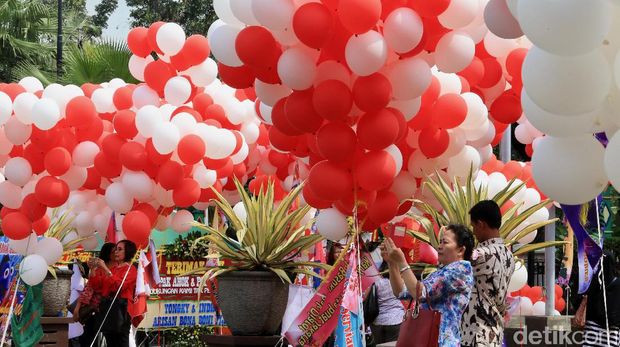 Warga barfoto di antara ratusan balón berwarna merah putin yang menghiasi pelataran Balai Kota, DKI Jakarta, Senin (8/5/2017). Fenomena balon ini usai ribuan karangan bunga untuk Gubernur DKI Jakarta Basuki Tjahaja Purnama beberapa hari terakhir.
