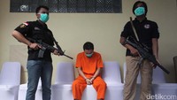 Tersangka yang masih hidup dikawal aparat kepolisian dengan senjata lengkap.