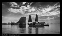 Kapal pesiar di Halong Bay yang agak gelap, kontras dengan langit di belakang yang terang dan dramatis membuat foto lebih menarik.