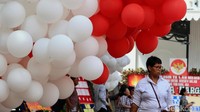 Seorang warga melintas di bawah balon merah-putih di taman halaman Balai Kota Jakarta.