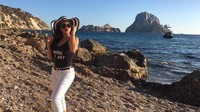 Ia tampil dengan celana warna putih yang di padu dengan tank-top hitam dan aksesoris dengan pemandangan indah di latar belakang foto tersebut. Dok. Instagram/arieltatum