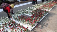 Seorang pendukung ahok menancapkan bunga di styrofoam bertuliskan Save Ahok.