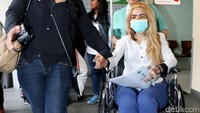 Sheila pun tampak mengenakan kemeja putih, jeans dan sandal jepit dan kursi roda saat keluar dari rumah sakit. Pool/Palevi S/detikFoto.