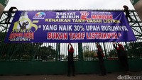 Massa membentangkan spanduk di pagar gedung DPR.