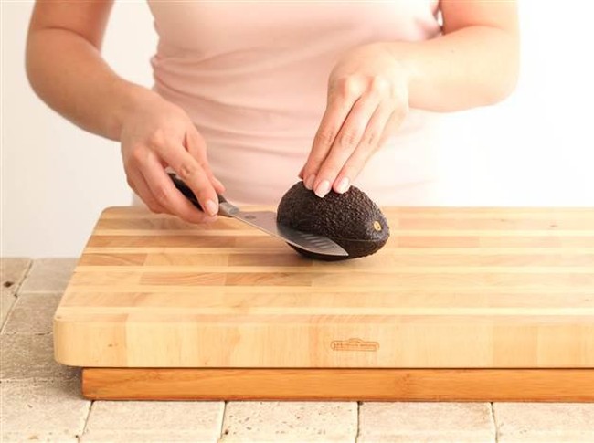 Woman slicing avocado for salad