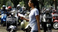 Seorang pengunjung melintas diantara Vespa yang terparkir.