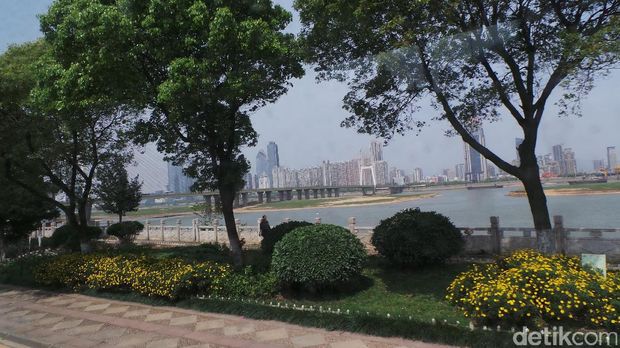 Nanchang di siang hari. Berlatar gedung pencakar langit dan taman kota.