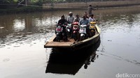 Perahu eretan yang mengangkut pengendara sepeda motor menyeberangi Kali Angke.