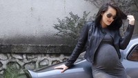 Atiqah tampak berdiri di samping mobil abu-abu dengan mengenakan dress pendek berwarna senada yang dipadukan bersama jaket dan kacamata hitam. Dok. Instagram/atiqahhasiholan