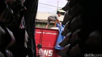 Pekerja membongkar truk berisi beras.