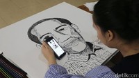 Seorang warga melukis wajah Presiden Jokowi.