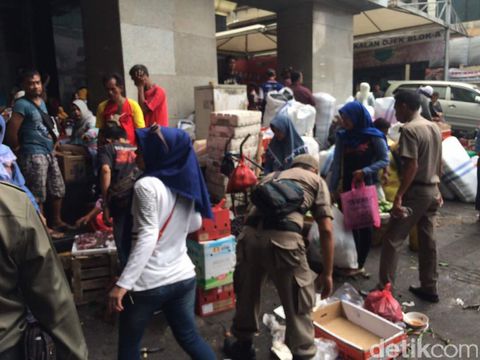 Para pedagang memindahkan dagangan mereka