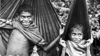 Dua bocah tengah berteduh menggunakan daun lontar di wilayah Indonesia bagian timur tahun 1950. Richard Harrington/Getty Images.