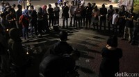 Para aktivis berdiri membentuk lingkaran sambil menyalakan lampu.