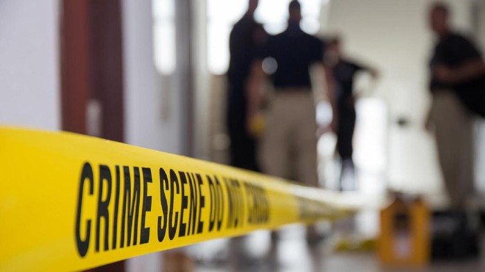 crime scene tape in building with blurred forensic team background