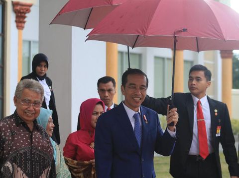 Jokowi memegang payung saat diguyur hujan