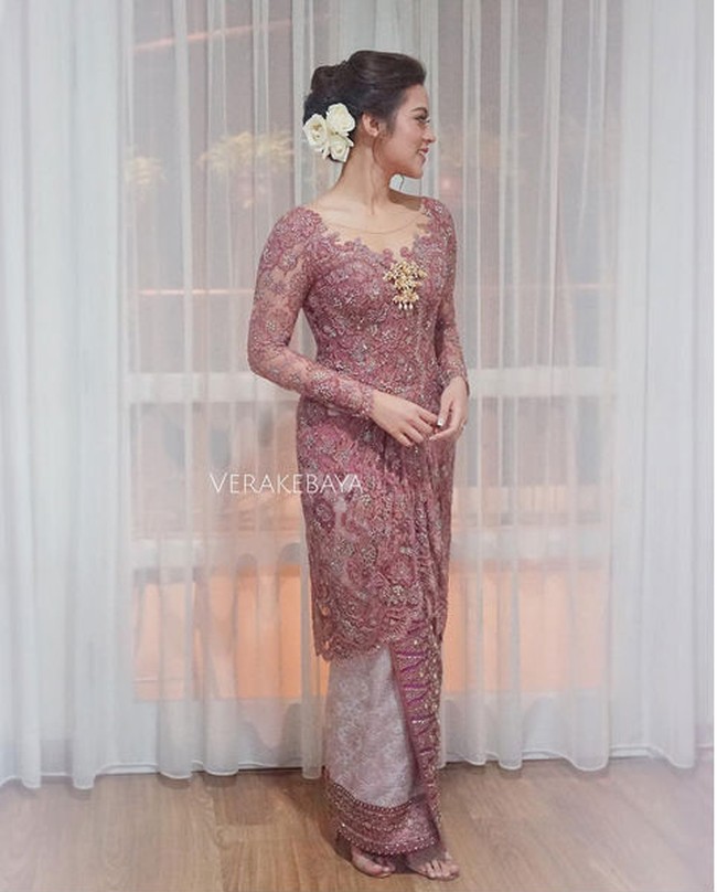 Di hari pertunangannya dengan Hamish Daud, kebaya dusty pink menjadi pilihan Raisa. Model kebaya kerah leher terbuka memperlihatkan teknik bordir cantik di atas tulle transparan, sedangkan bagian belakang kebaya dipotong backless yang tampak modern. Ia mempercayakan desain kebayanya pada Vera Kebaya, dan memakai kain tenun metalik sebagai paduan. Foto: Dok. Instagram/Vera Kebaya