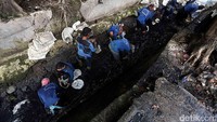 Pasukan biru mengeruk lumpur yang mengendap di saluran air.