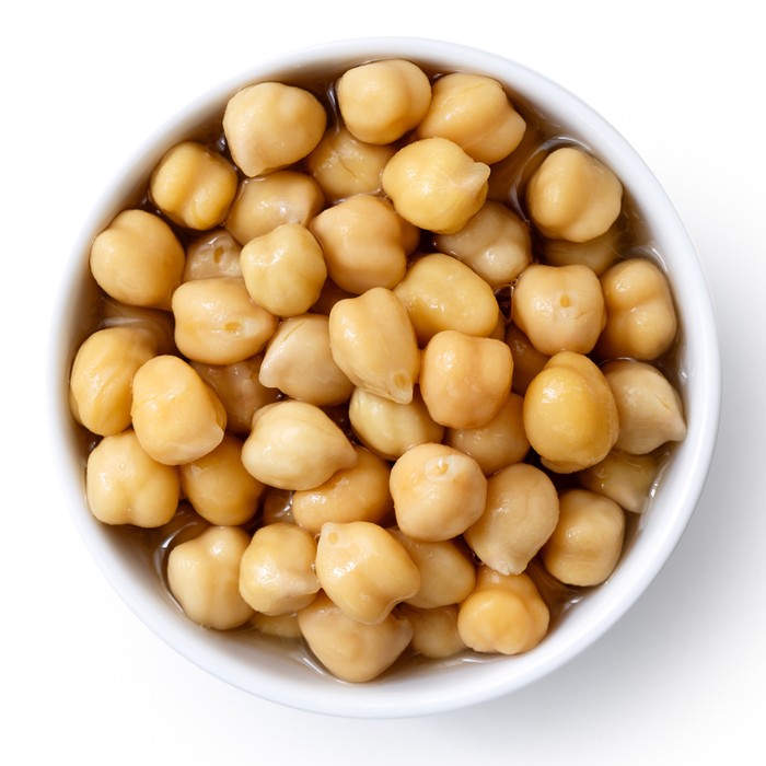 Cooked chickpeas in white bowl isolated on white from above.