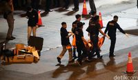 Kantong berwarna oranye diangkut ke ambulans.