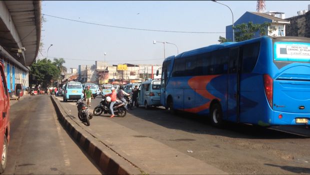 Bus dan angkot di Kampung Melayu sibuk menaikkan dan menurunkan penumpang.