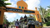 Sebuah kendaraan angkutan umum yang membawa warga melewati sebuah gerbang Marawi menuju sebuah pusat evakuasi setelah pasukan pemerintah melanjutkan serangan kepada militan terkait ISIS yang telah mengambil alih sebagian besar kota Marawi, Filipina Selatan. REUTERS / Romeo Ranoco
