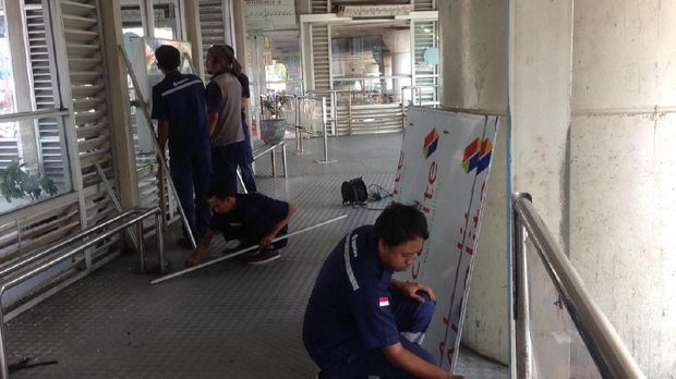 Petugas mengganti kaca halte yang pecah akibat ledakan bom.