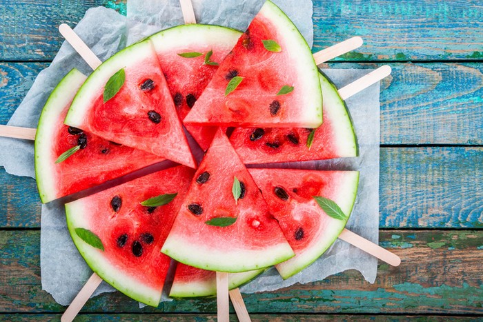 Slices of fresh juicy watermelon on a paper closeup on rustic wooden table