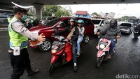 Seorang polisi memberhentikan pengendara sepeda motor untuk diperiksa surat-suratnya.