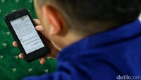 Seorang pengunjung tengah menghabiskan waktu dengan bertadarus.