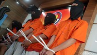 Para tersangka dihadirkan dengan memakai baju tahanan dan penutup kepala.