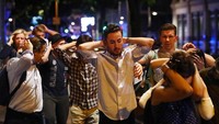 Pejalan kaki mengangkat tangan di belakang kepala saat melintasi lokasi serangan teror. (Reuters / Neil Hall)