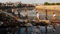 Sejumlah warga di Mumbai terlihat melintas di atas sungai yang penuh dengan tumpukan sampah. REUTERS/Danish Siddiqui.