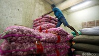 Pedagang menumpuk bawang putih di kiosnya di Pasar Induk Kramat Jati.