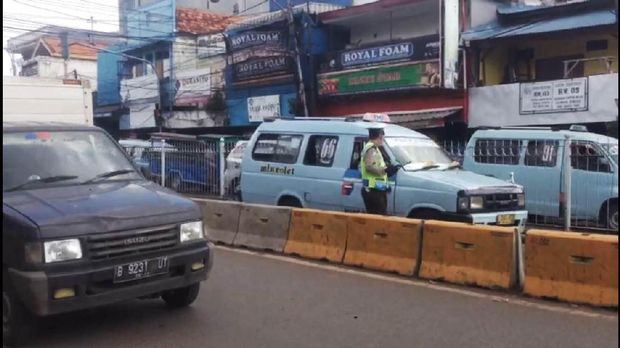 Polisi menindak pengendara yang masuk jalur TransJakarta.