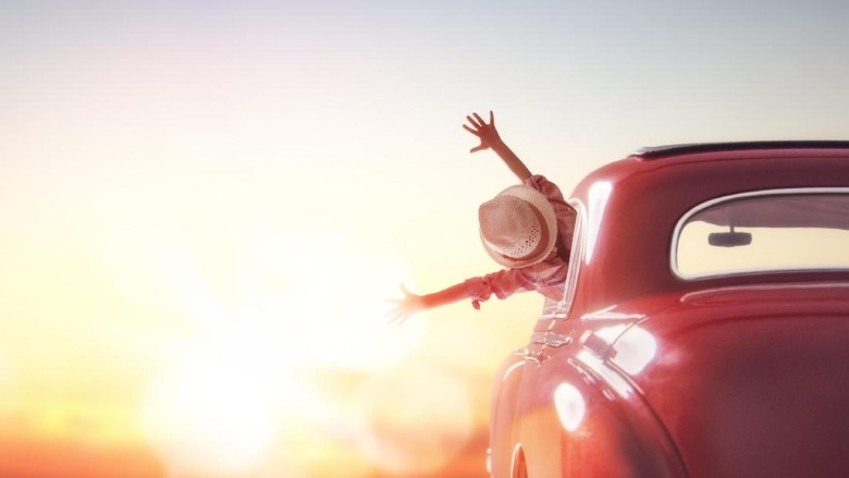 521463772 Toward adventure! Girl relaxing and enjoying road trip. Happy girl rides into the sunset in vintage car.