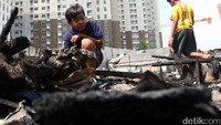 Seorang anak mengais di sisa kebakaran.